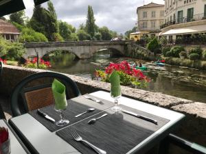 a table with two wine glasses and a view of a river at Le Coligny in Brantôme