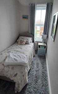 a small bedroom with a bed and a window at Dune Cottage in Caister-on-Sea