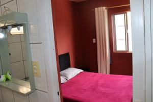 um quarto com uma cama rosa e um espelho em Casa de praia da Kenna, centro em Navegantes