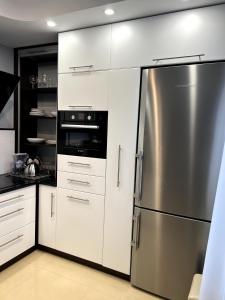 a kitchen with white cabinets and a stainless steel refrigerator at Apartament Tuwima 6 in Ełk