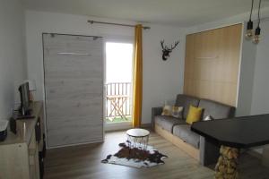 a living room with a couch and a sliding door at Studio Cocooning tout confort Les Angles in Les Angles