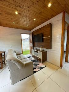 sala de estar con sofá y TV de pantalla plana en Casa Em Ponta Das Canas, en Florianópolis