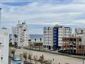Una vista de una ciudad con edificios y el océano. en Cité Jardins Appartement, en Martil