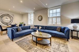 a living room with a blue couch and a table at The Penthouse - Allocated Parking with City Views in Ripon
