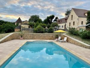 una piscina con ombrellone e una casa di Charming 19th Century Farmhouse with Pool a Vitrac