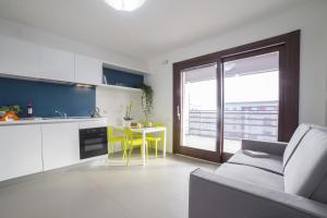 a kitchen with a couch and a table with yellow chairs at Aurum Aparthotels Bicocca in Milan