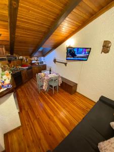 een woonkamer met een tafel en een tv aan de muur bij Casa vacanza Folgarida in Folgarida
