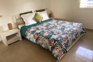 1 dormitorio con 1 cama con un edredón colorido en Sunset Lodge SXM - T2, cosy, piscine, vue lagon & bons plans en Marigot