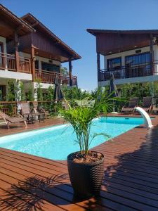 a potted plant sitting on a deck next to a pool at Pousada Rosa Maria in Praia do Rosa
