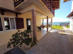 a house with a patio with a view of the ocean at Férias e alegrias em casa pé na areia! in Penha