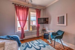 Un dormitorio con una cama y una silla y un televisor. en Splendid Colonial in Midtown with Parking, en Memphis