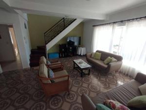 a living room with a couch and chairs and a staircase at Férias e alegrias em casa pé na areia! in Penha