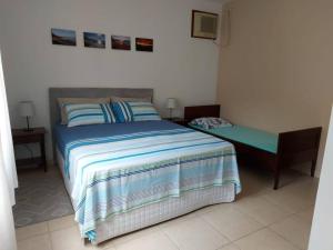 1 dormitorio con cama y banco. en Férias e alegrias em casa pé na areia!, en Penha