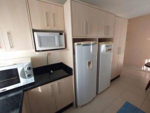 a kitchen with two refrigerators and a microwave at Férias e alegrias em casa pé na areia! in Penha