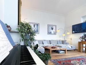 sala de estar con piano y sofá en Appartement spacieux & calme avec vue sur l'Escaut, en Tournai