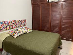 a bedroom with a green bed and wooden cabinets at Quartos Anavilhanas in Novo Airão