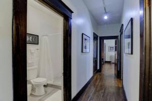 a bathroom with a toilet and a hallway at 1900's Historic Getaway - Prime Midtown Location! in Memphis +39 photos