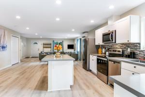a kitchen with white cabinets and a living room at Salt, Sand, Surf, Repeat in Westport
