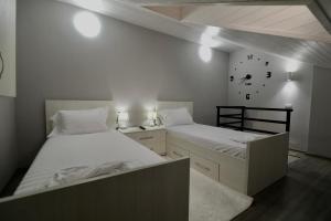 a bedroom with two beds and a clock on the wall at Old Town Inn in Pogradec