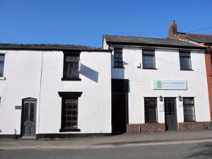 a white building on the side of a street at Lymm Cottage in Lymm