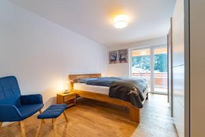 ein Schlafzimmer mit einem Bett und einem blauen Stuhl in der Unterkunft Ferienwohnung Feldberg Schwarzwald in Feldberg