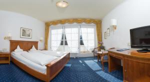 a bedroom with a bed and a desk and a television at Park Hotel Bellevue in Dobbiaco