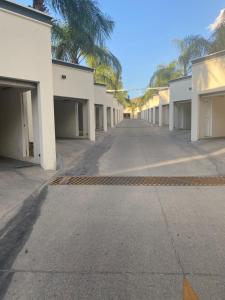 an empty parking lot with white buildings and palm trees at Motel isis in Guadalajara