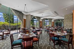 a restaurant with tables and chairs and windows at Millennium Hotel Queenstown in Queenstown