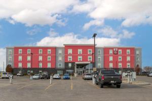 un gran edificio rojo con coches estacionados en un estacionamiento en Best Western Plus Airport Inn & Suites en Saskatoon