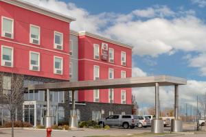 a red building with a parking lot in front of it at Best Western Plus Airport Inn & Suites in Saskatoon