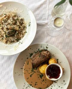 two plates of food with meat and potatoes on a table at Götaströms Värdshus in Skillingaryd