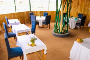 ein Esszimmer mit weißen Tischen und blauen Stühlen in der Unterkunft Amanya Camp 1-Bed Tent Elephant Suite in Amboseli in Amboseli-Nationalpark