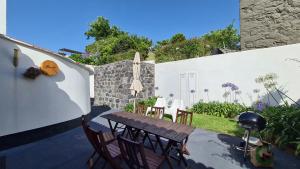 a patio with a table and chairs and a wall at Casas D'Arramada in Ribeira Funda