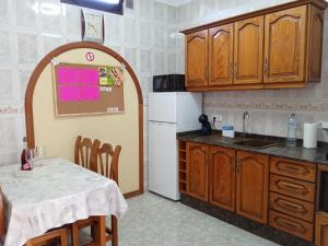 a kitchen with a table and a white refrigerator at adosado cerca del mar in Playa Honda
