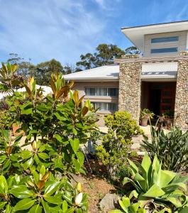a house with a bunch of plants in front of it at Serenity Lodge for Couples in Ulladulla