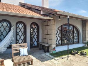 a small house with a porch with a swing at Casa Confortável in Xangri-lá