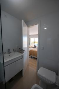 a bathroom with a sink and a toilet and a bedroom at SYRAH Premium B2 - Piscina privada con vista al mar by depptö in Punta del Este