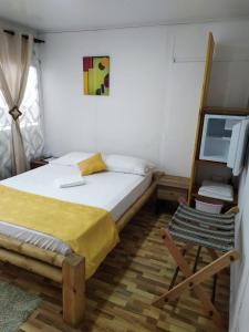 a bedroom with a bed and a chair and a television at Posada San Nicolas in San Andrés
