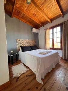 a bedroom with a large white bed with wooden ceilings at Hosteria Isabel in Las Grutas