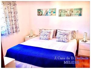 1 dormitorio con 1 cama grande con sábanas y almohadas azules en A Casa da Ti Deolinda, en Melides