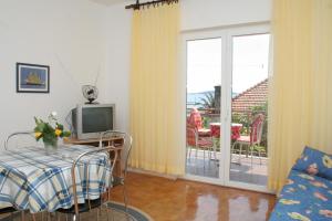 ein Wohnzimmer mit einem TV und einer Glasschiebetür in der Unterkunft Apartments by the sea Orebic, Peljesac - 10436 in Orebić