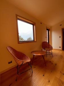 two chairs and a table in a room with a window at Refugio Pullao in Quilquico