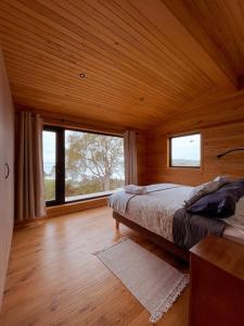 a bedroom with a bed and a large window at Refugio Pullao in Quilquico