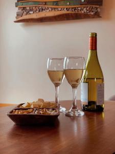 une table avec deux verres de vin et une assiette de fromage dans l'établissement Refugio Pullao, à Quilquico