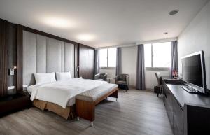 een hotelkamer met een bed en een flatscreen-tv bij Hotel Bonza in Zhubei