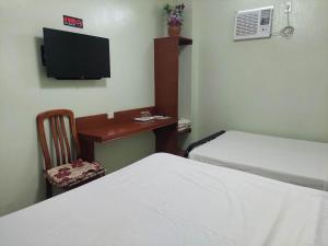a room with two beds and a desk with a tv at Dweller's Pensione in Iloilo City