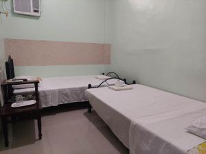 two beds in a room with a tv and a table at Dweller's Pensione in Iloilo City