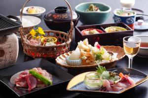 a table with plates of food and glasses of wine at Ryokan Chinsen-Rou in Nantan city