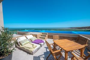eine Terrasse mit einem Holztisch und Stühlen sowie einem Tisch und einem Tisch in der Unterkunft SYRAH Premium B2 - Piscina privada con vista al mar by depptö in Punta del Este