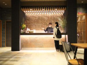 un hombre y una mujer de pie en un bar en HOTEL CUORE Kyoto Shijo Omiya en Kioto